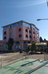 a pink building with a tennis court in front of it at Hotel Meteor in Shkodër