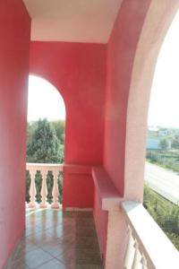 a room with a red wall and a balcony at Hotel Meteor in Shkodër