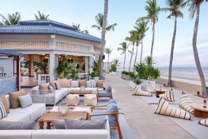 eine Terrasse des Resorts mit Sofas, Tischen und Palmen in der Unterkunft Dusit Thani Hua Hin in Cha-am