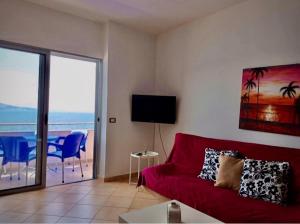 a living room with a red couch and a balcony at Saranda Rooms - Port in Sarandë