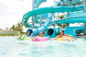 three girls in the water on a water slide at Hyatt Ziva Riviera Cancun All-Inclusive in Puerto Morelos