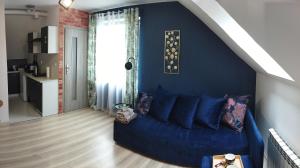 ein blaues Sofa im Wohnzimmer mit blauer Wand in der Unterkunft Apartament na Glinkach 22 in Augustów