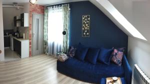a blue couch in a living room with a blue wall at Apartament na Glinkach 22 in Augustów