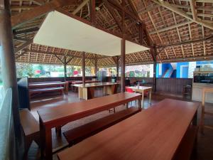 um restaurante com mesas de madeira e bancos numa sala em Villa Batu Tua Puncak Mitra RedDoorz em Bogor