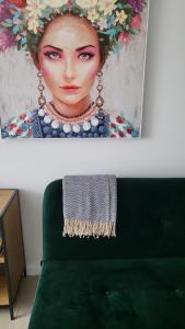 a painting of a woman with a hat on top of a green couch at Apartament Mochnackiego in Olsztyn