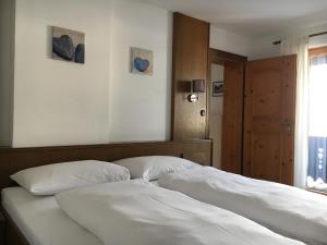 a bedroom with a bed with white sheets and a window at Landhaus Holzereck in Ehrwald