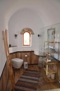 a bathroom with a toilet and a sink and a window at Venus Hill Guest House in Lefkogeia