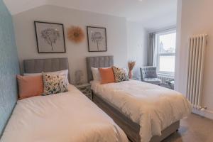 a bedroom with two beds and a chair and a window at Carrick Rooms in Port Saint Mary