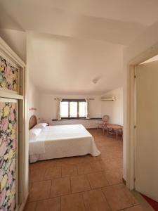 a bedroom with a white bed and a window at Locanda Rosella in Giba