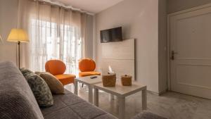 ein Wohnzimmer mit einem Sofa und zwei orangefarbenen Stühlen in der Unterkunft Apto. City Hall in Córdoba
