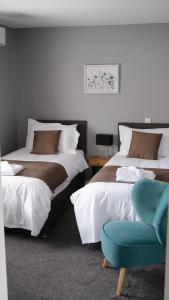 a bedroom with two beds and a blue chair at Horizon View Portstewart Tourist Board approved in Portstewart