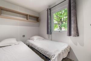 due letti in una stanza con finestra di Les Mobil-homes By Le Marintan a Saint-Michel-de-Maurienne