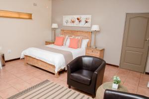 a bedroom with a bed and a leather chair at 85 Ehmke Guesthouse in Nelspruit