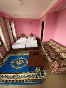 a room with two beds and a table in it at The Nest Guest House in Changunarayan