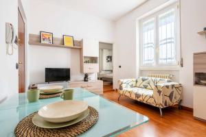 uma sala de estar com uma mesa de vidro e um sofá em Cozy apartament in Piazza 5 Giornate by Easylife em Milão