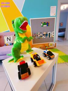 Legoland-Happy Wonder Love Suite-Elysia- Max8pax-with Garden-Pool view في نوساجايا: لعبة ديناصور تجلس على طاولة بجانب ألعاب السيارات