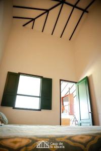 a bedroom with green shuttered windows and a bed at Hotel Campestre Casa de la Abuela in La Capilla