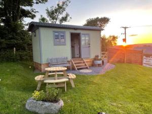 a tiny house with a picnic table in a yard at Luxury Shepherd Hut on small South Hams farm, Devon in Modbury