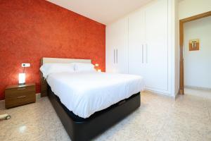 a bedroom with a large bed and a red wall at Hauzify I Apartament Cala Pepo 1 in L'Ametlla de Mar