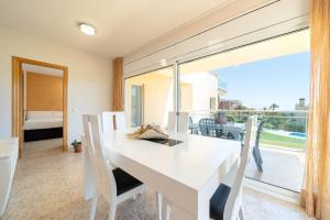cocina con mesa y sillas blancas y ventana grande en Hauzify I Apartament Cala Pepo, en L'Ametlla de Mar