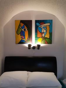 tres pinturas en una pared sobre una cama en Studio Toma with private parking place, en Šibenik