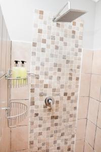 a bathroom with a shower with a tiled wall at 85 Ehmke Guesthouse in Nelspruit