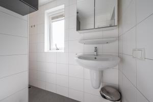 a white bathroom with a sink and a window at Zeester in Serooskerke +24 photos