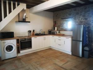 - une cuisine avec des placards blancs et un lave-linge/sèche-linge dans l'établissement Maison Normande proche de la mer et des lieux touristiques, à Quettehou