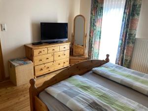 1 dormitorio con 2 camas y un tocador con TV en Oberegghof, en Wagrain