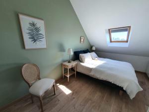 ein Schlafzimmer mit einem großen Bett und einem Stuhl in der Unterkunft Le Clos de Baron sur Odon, un havre de paix. in Baron-sur-Odon