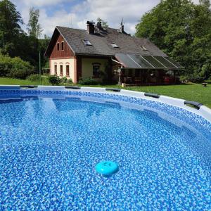 a blue swimming pool in front of a house at Apartmany Chribska in Chřibská