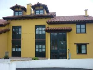 ein gelbes Haus mit schwarzen Fenstern und einem Dach in der Unterkunft EL HOGAR DE LA CASTAÑERA in Colombres