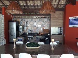 eine Küche mit einem Tisch mit weißen Stühlen und 2 Leuchten in der Unterkunft Sol, mar e natureza perto de você. in Itacimirim