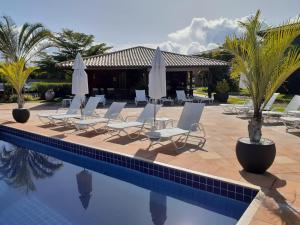 eine Gruppe von Stühlen und Sonnenschirmen neben einem Swimmingpool in der Unterkunft Sol, mar e natureza perto de você. in Itacimirim
