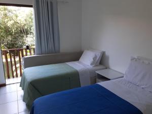 1 Schlafzimmer mit 2 Betten und einem Balkon mit Fenster in der Unterkunft Sol, mar e natureza perto de você. in Itacimirim + 30 Fotos