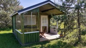 a green cabin with a chair on a deck at Kastani Camping in Haapsalu