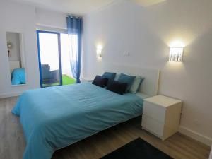 sypialnia z łóżkiem z niebieską pościelą i oknem w obiekcie Rocha SPOT w mieście Portimão