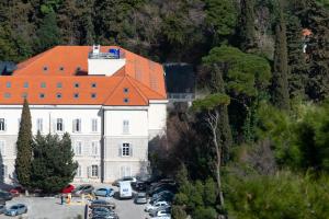 a large building with an orange roof in a parking lot at Dubrovnik Central Accommodation in Dubrovnik