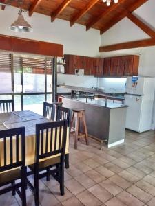 eine Küche mit einem Tisch und Stühlen sowie einem Kühlschrank in der Unterkunft Casa quinta chivilcoy El Silencio in Chivilcoy