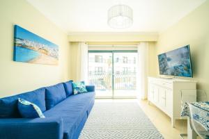 - un canapé bleu dans le salon doté d'une fenêtre dans l'établissement Albufeira - Cerro Mar Star - Cozy and Relaxing T1, à Albufeira
