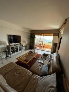 uma sala de estar com um sofá castanho num quarto com vista em Une terrasse sur Monaco logement 2 chambre em Beausoleil