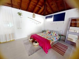 TabayescoにあるEco Casa Alma,Montaña, Campo y Playaのベッドルーム1室(ピンクの毛布付きのベッド1台付)