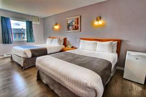 a hotel room with two beds and a window at Hotel-Motel La Difference in Sainte-Marie