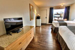a hotel room with two beds and a flat screen tv at Hotel-Motel La Difference in Sainte-Marie
