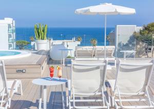 eine Terrasse mit Stühlen, einem Sonnenschirm und einem Pool in der Unterkunft Marins Playa in Cala Millor