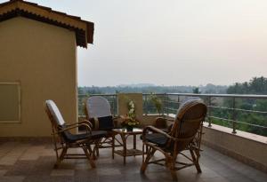 a patio with three chairs and a table on a balcony at Boshan Hotels in Mapusa