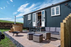 a green tiny house with a patio and a grill at Inglewood Shepherd's Huts in Penrith