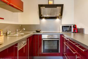 Una cocina con gabinetes rojos y un horno de acero inoxidable. en Résidence Egalité - Montmartre, en Dijon 9 fotos más