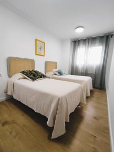 two beds in a room with white walls and wood floors at Apartamento Santander Maliaño in Maliaño