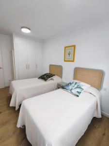 Habitación con 2 camas, paredes blancas y suelo de madera. en Apartamento Santander Maliaño, en Maliaño